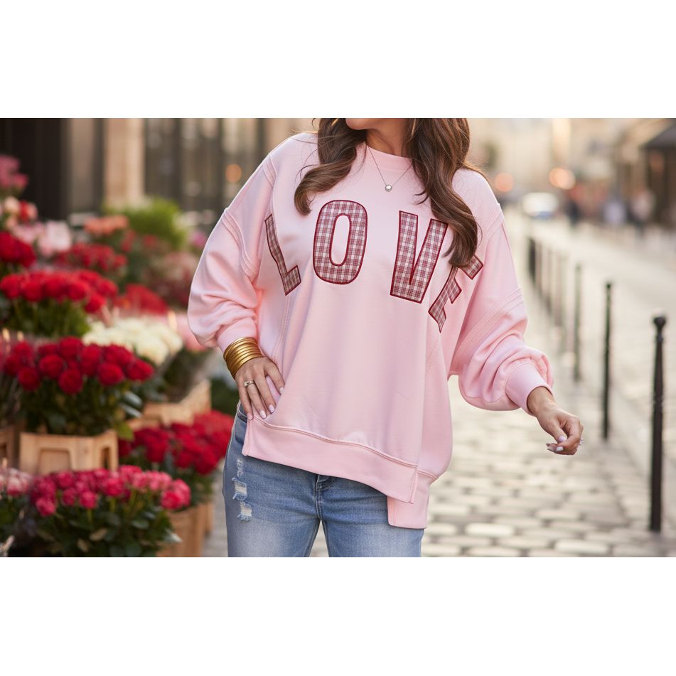Person wearing a pink sweatshirt with 'LOVE' printed in red plaid letters, standing outdoors.