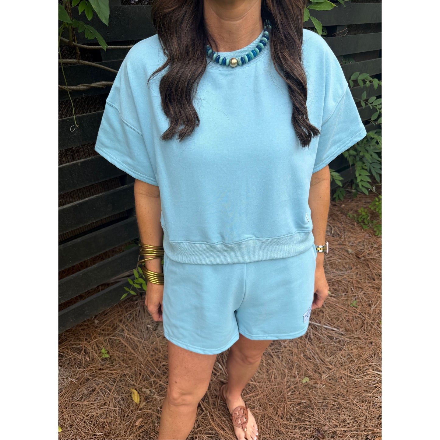 Person wearing a light blue dress sitting on a bench with a natural background