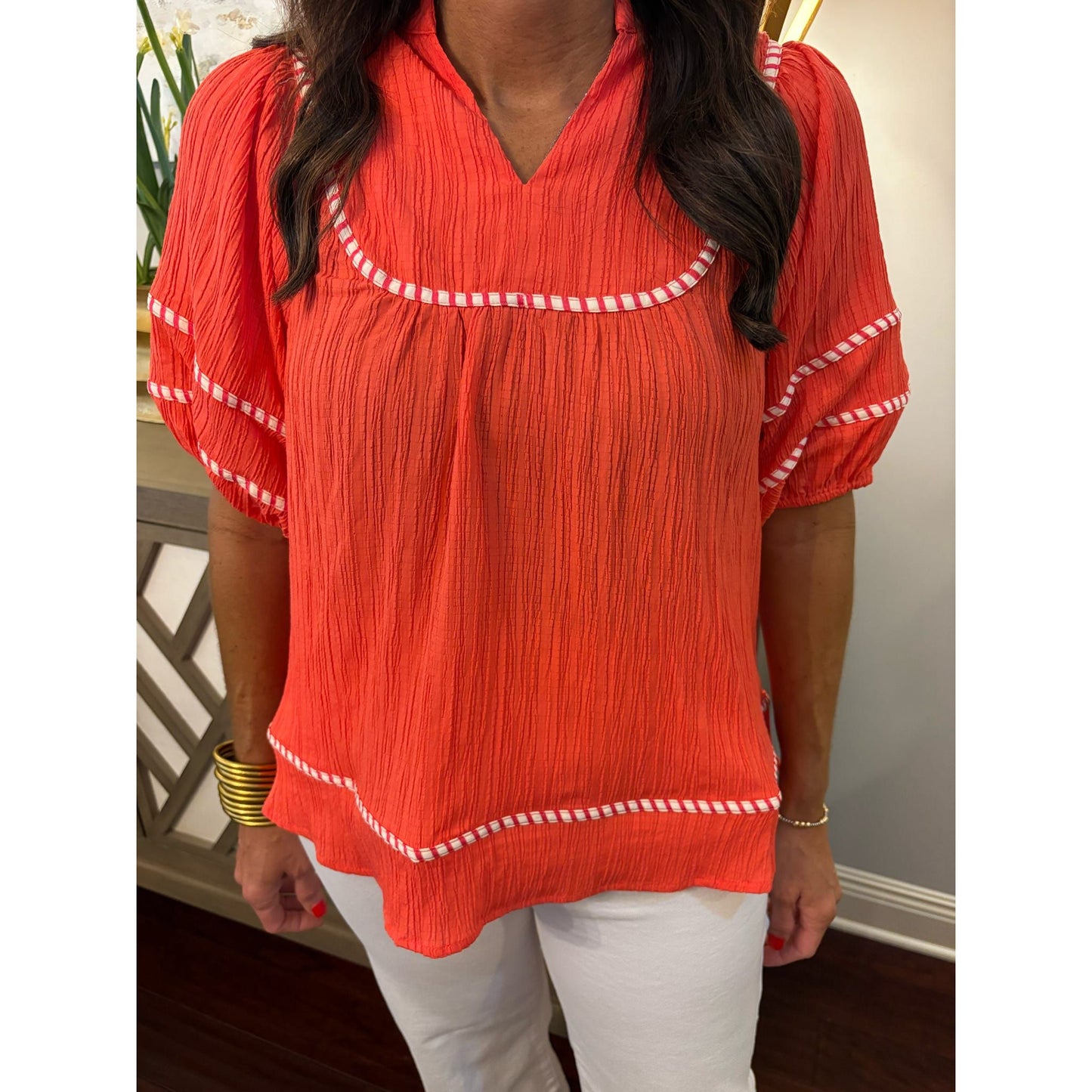 Person wearing a red blouse with white trim indoors