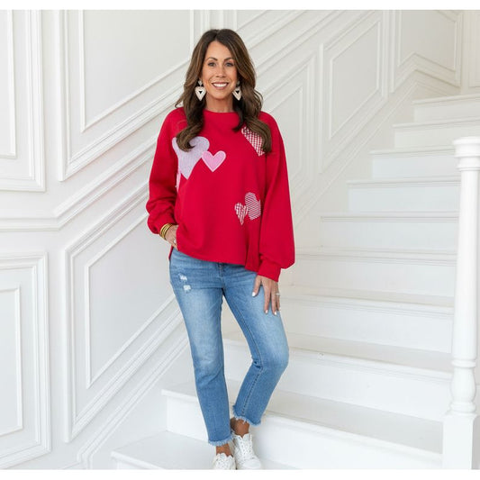 Woman wearing a red sweater with heart patterns standing on a staircase.