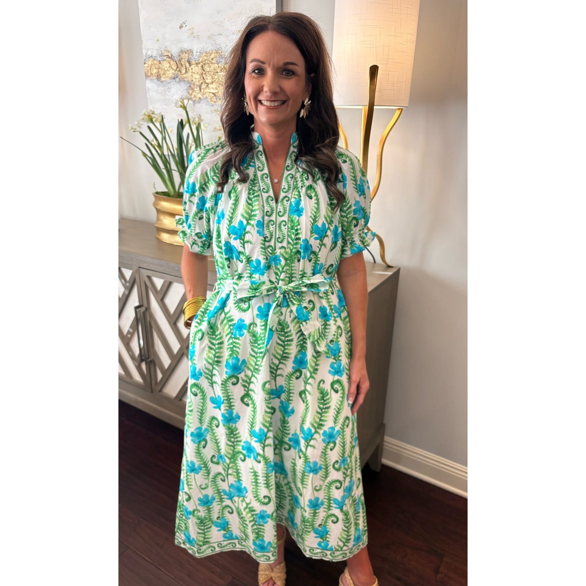 Woman wearing a green and blue floral dress in an indoor setting.