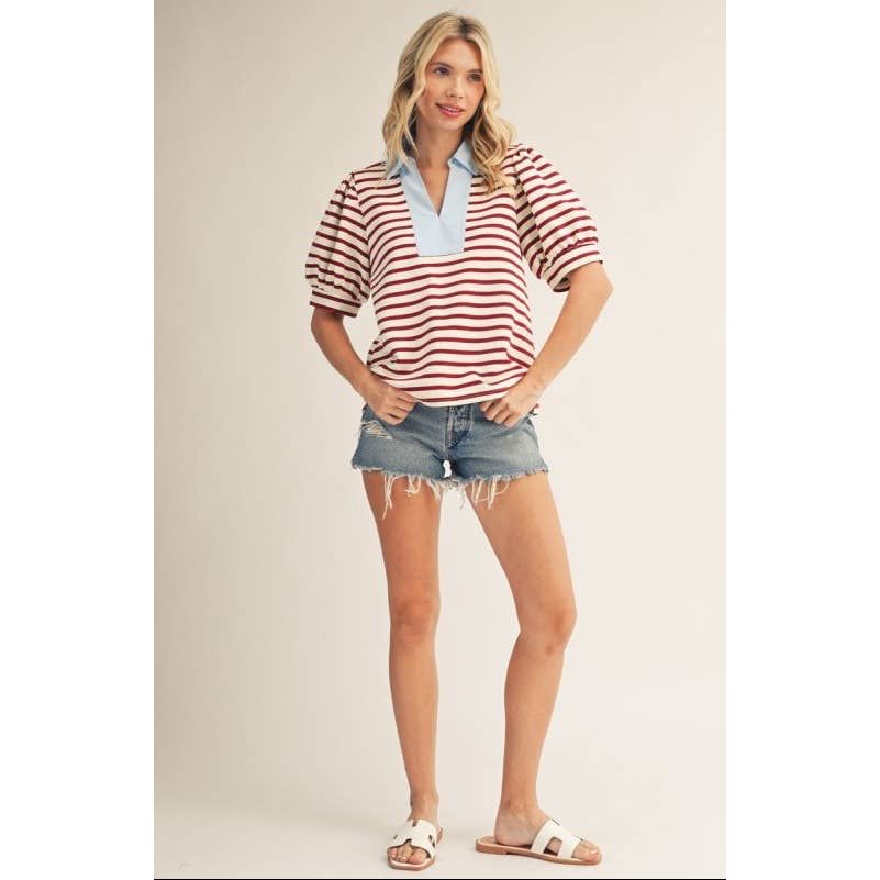Woman wearing a red and white striped shirt with denim shorts on a plain background