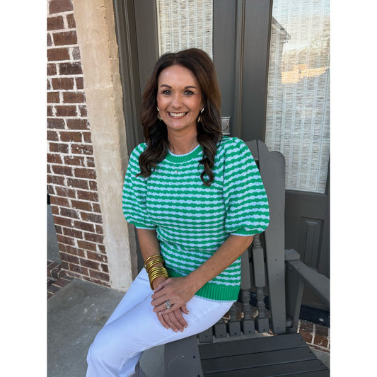 Woman wearing a green and white striped sweater sitting on a porch.