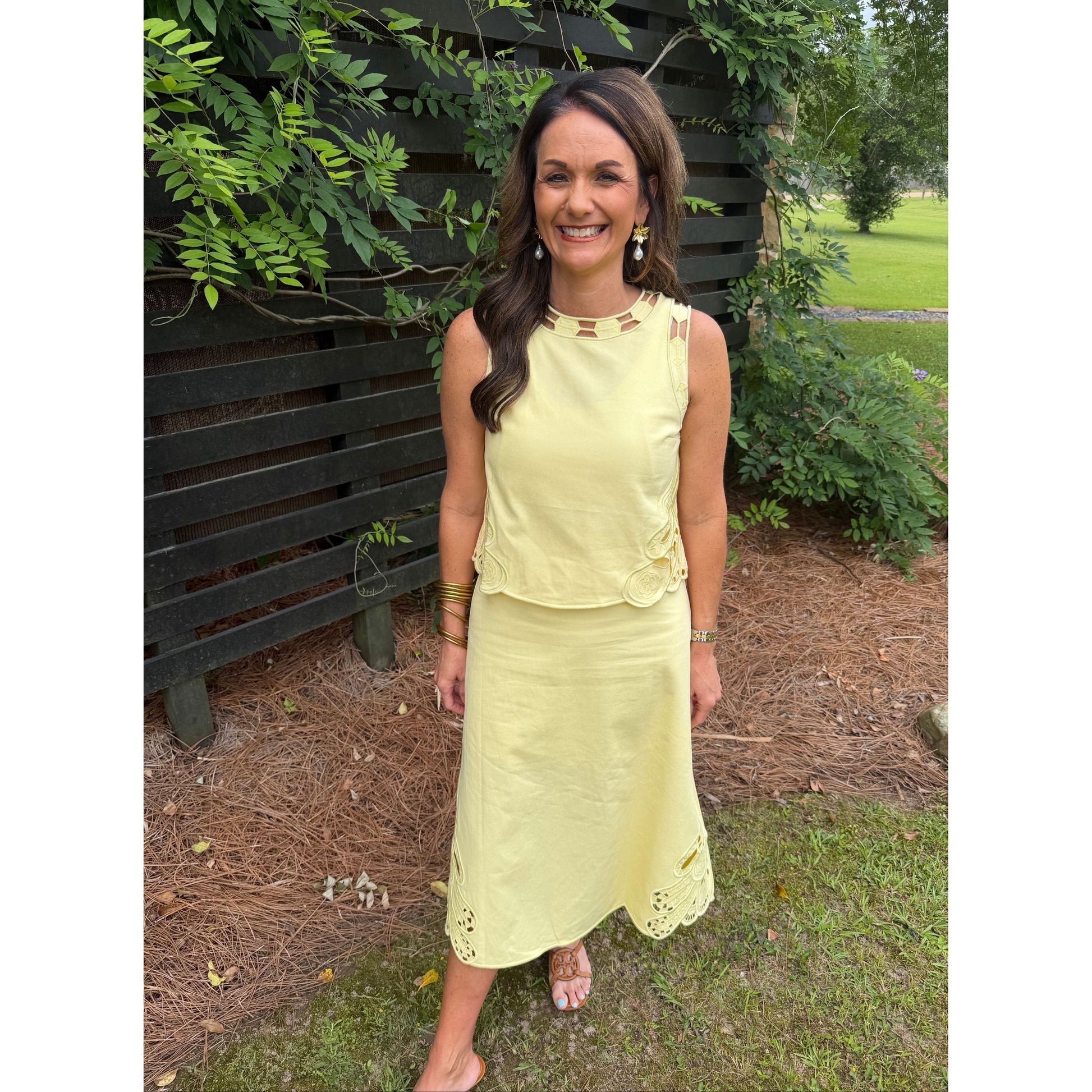 Woman in a yellow dress standing outdoors with greenery around