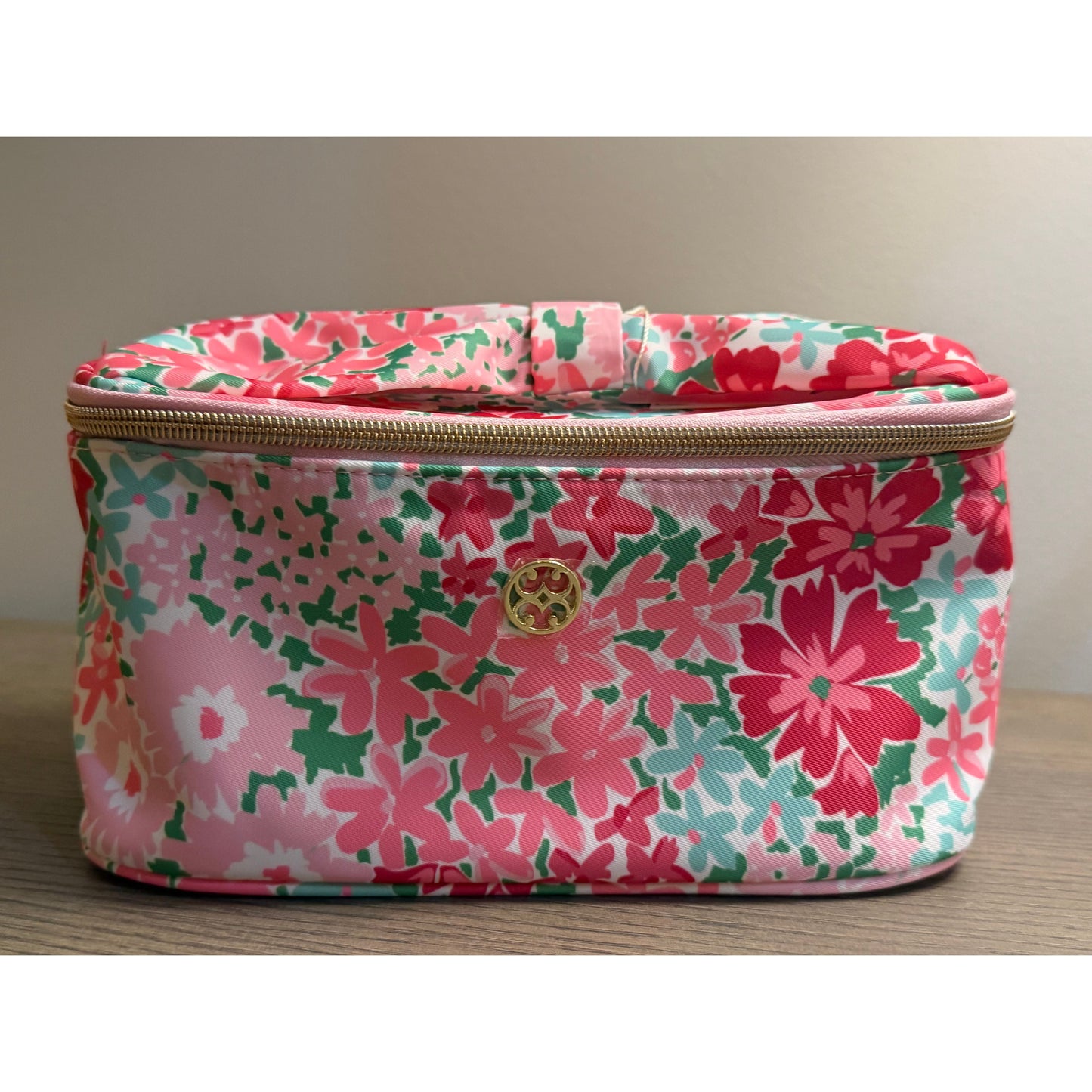 Floral-patterned cosmetic bag with a gold zipper on a neutral background