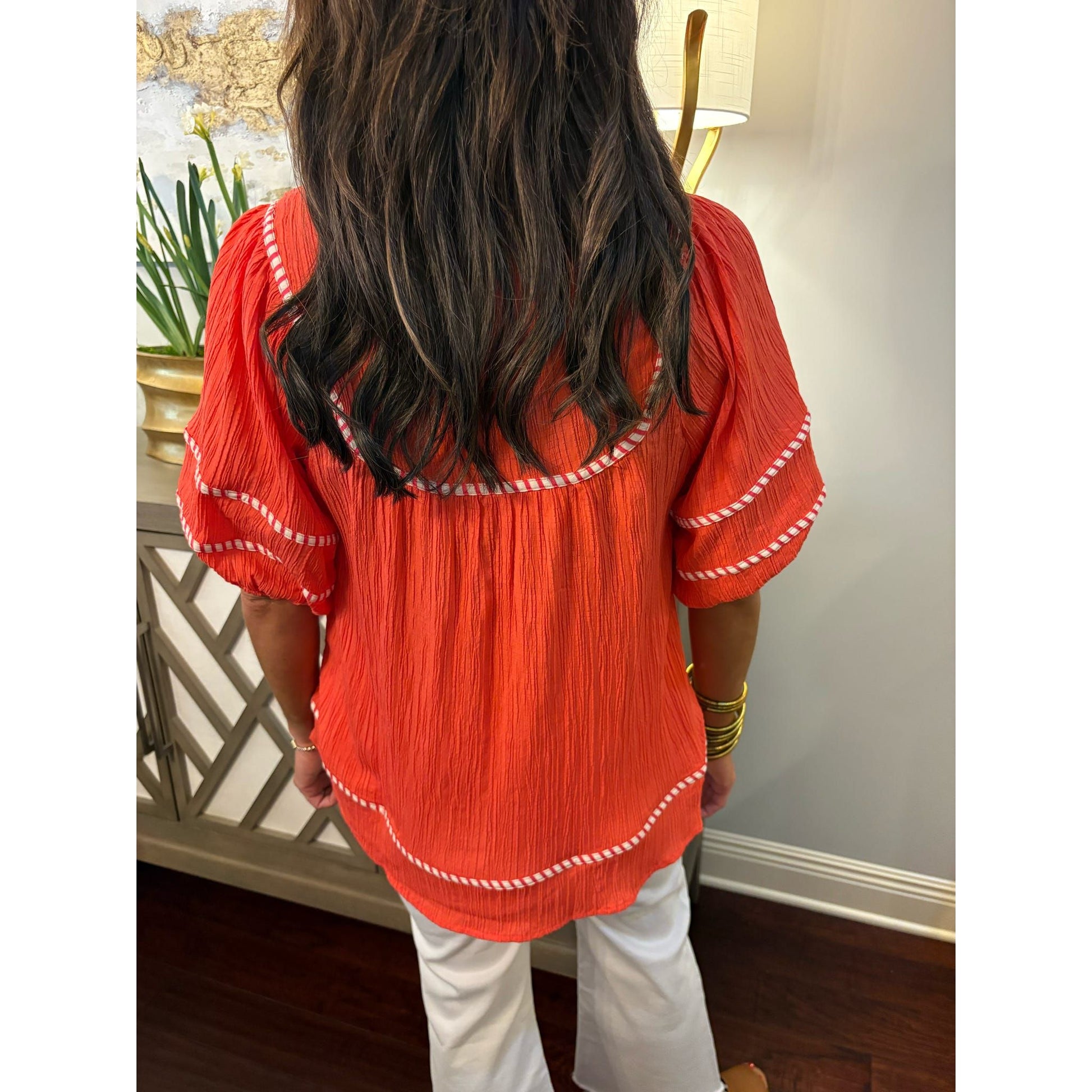 Person wearing a red blouse with white trim in an indoor setting