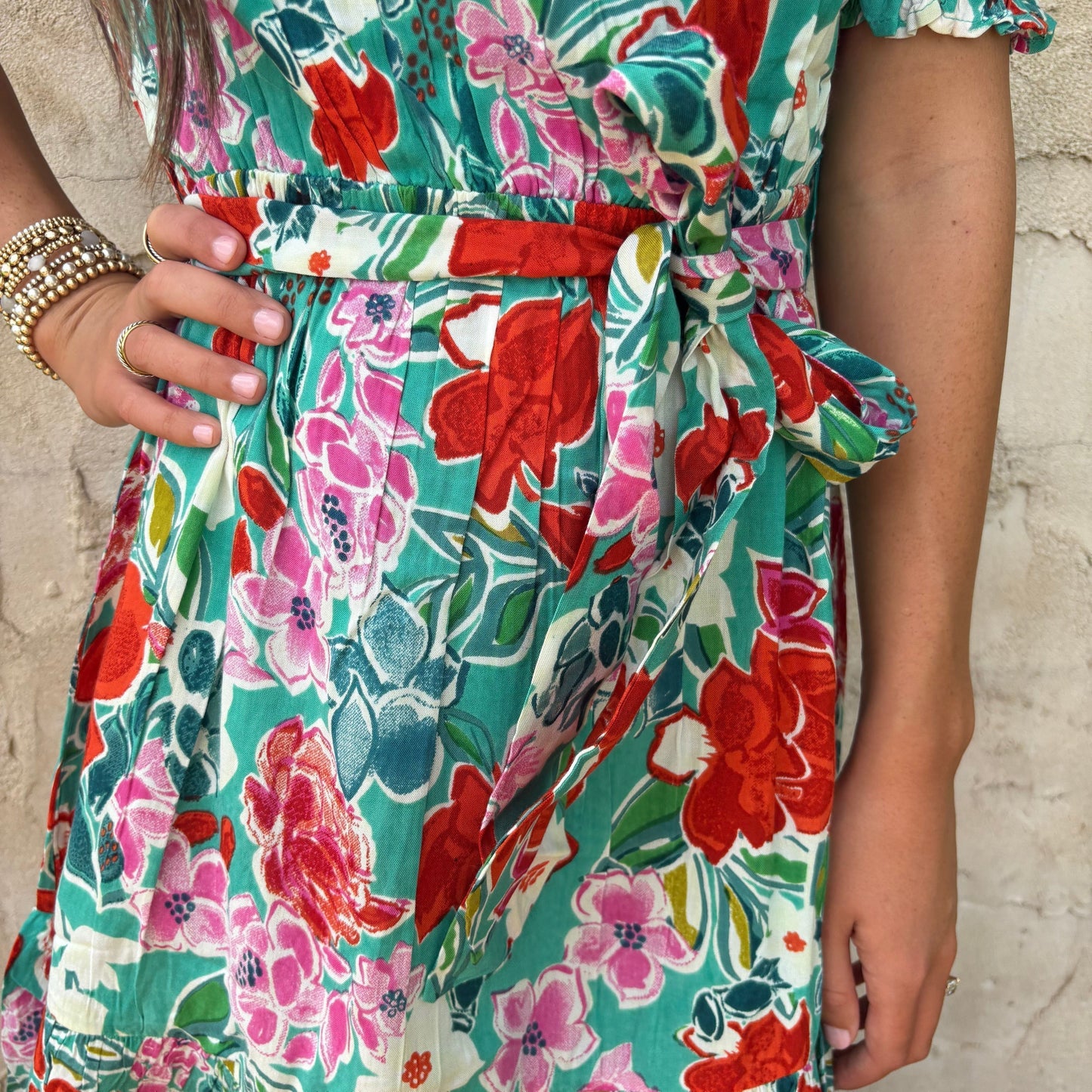 Close-up of a colorful floral dress with a stone wall background
