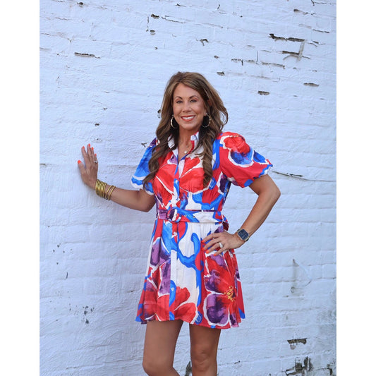 Woman wearing a colorful dress against a white brick wall