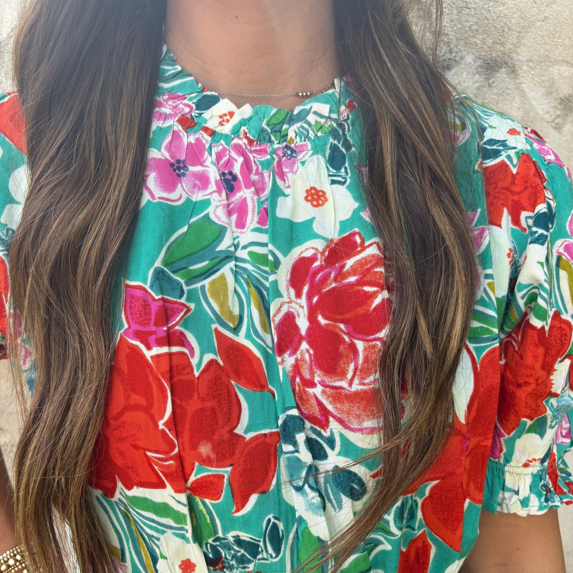 Close-up of a person wearing a colorful floral dress with long hair.