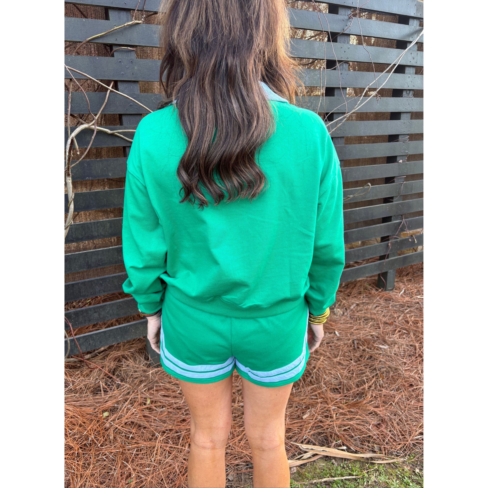Person wearing a green jacket with a horse's head visible, standing on a wooden platform.