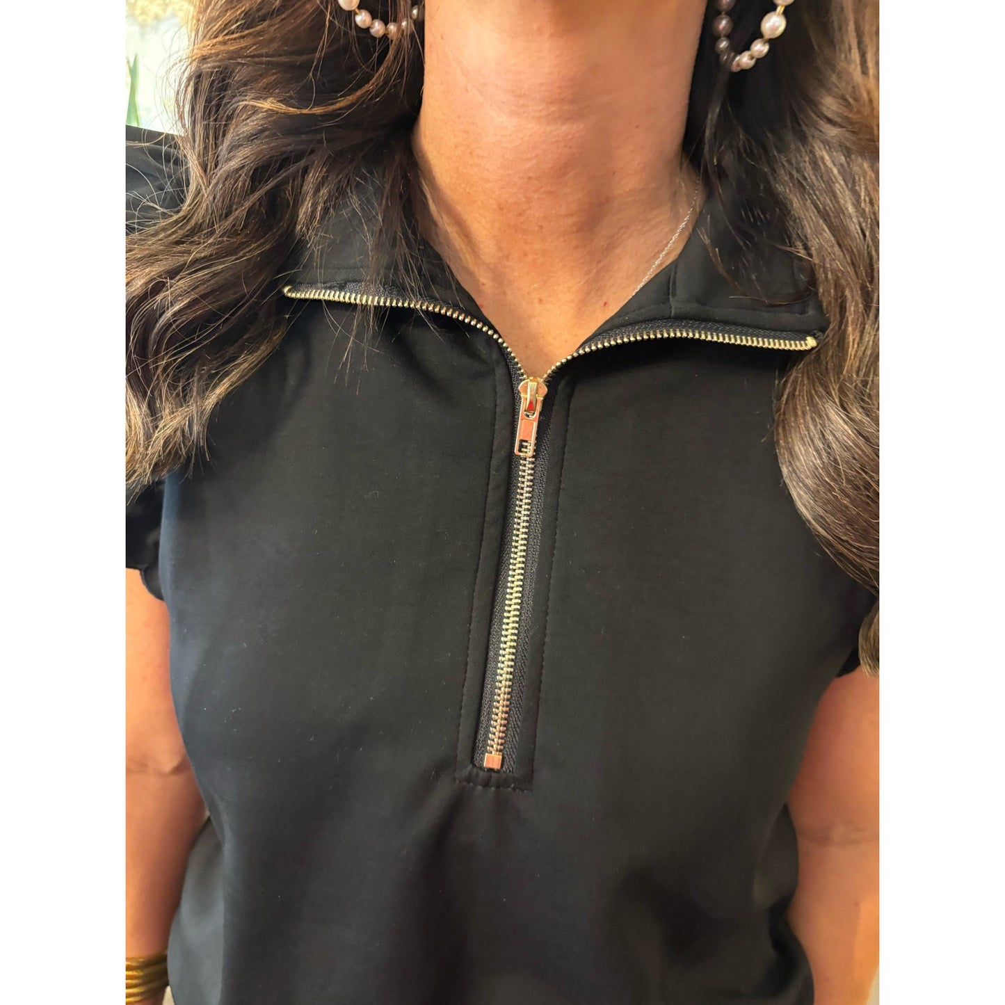 Person wearing a black quarter-zip shirt with a zipper detail.