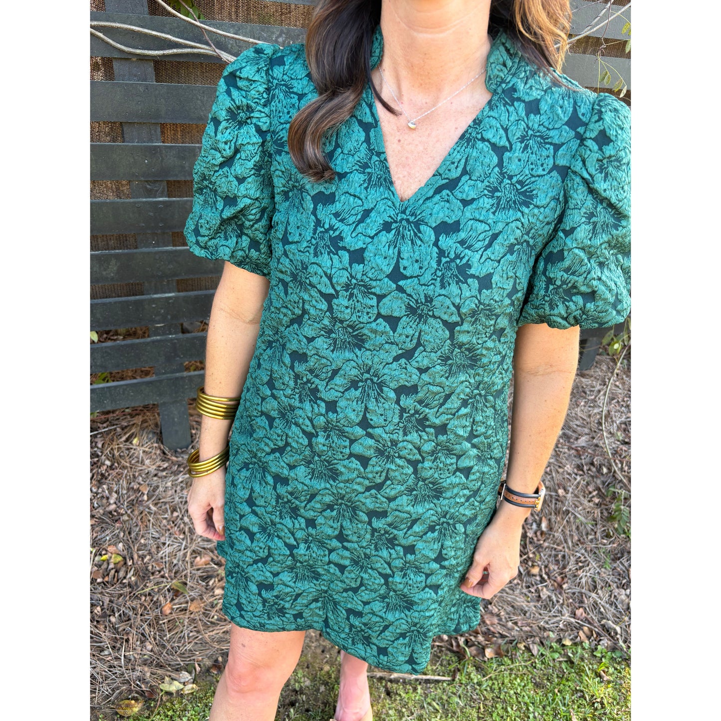 Person holding a green floral-patterned bag outdoors