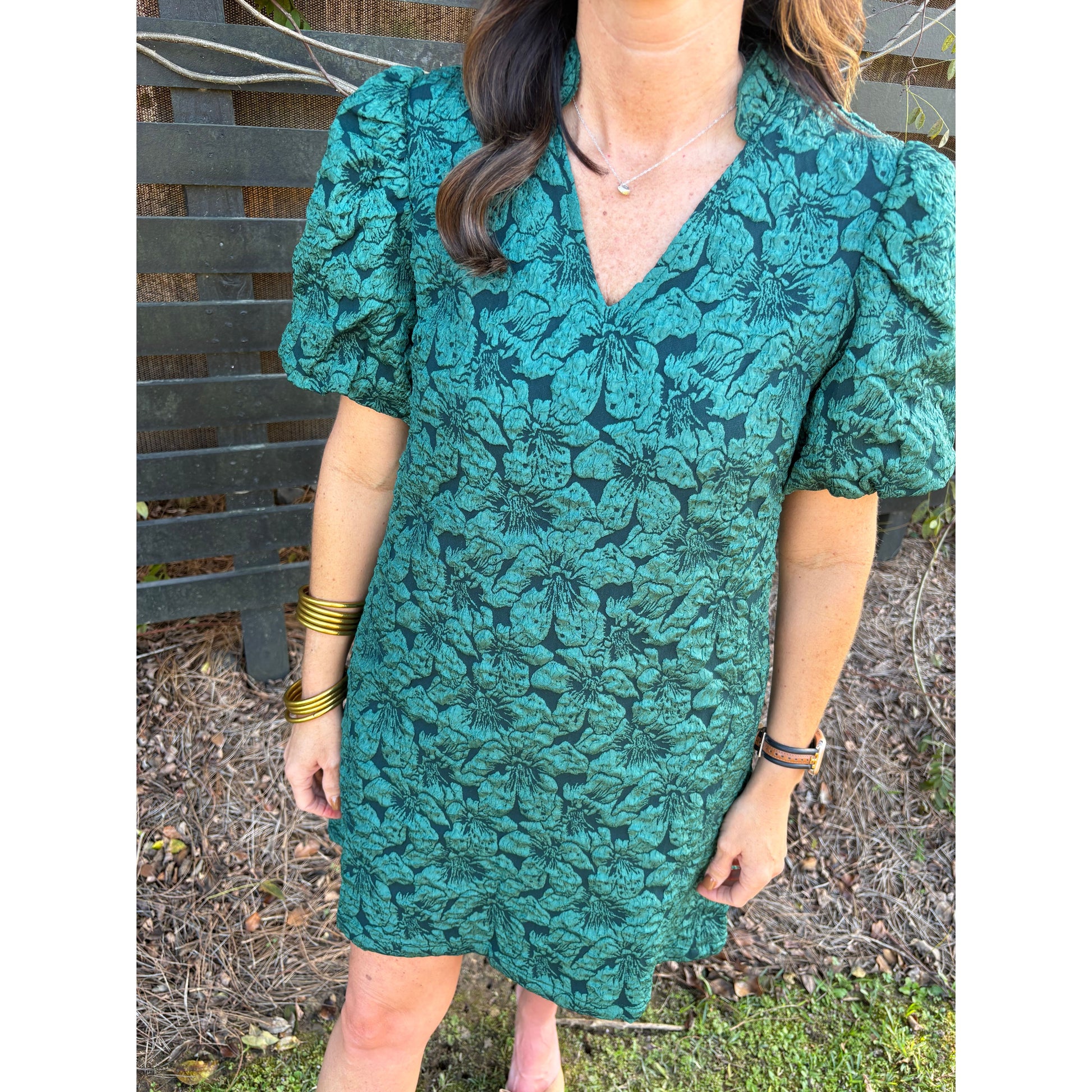 Person holding a green floral-patterned bag outdoors