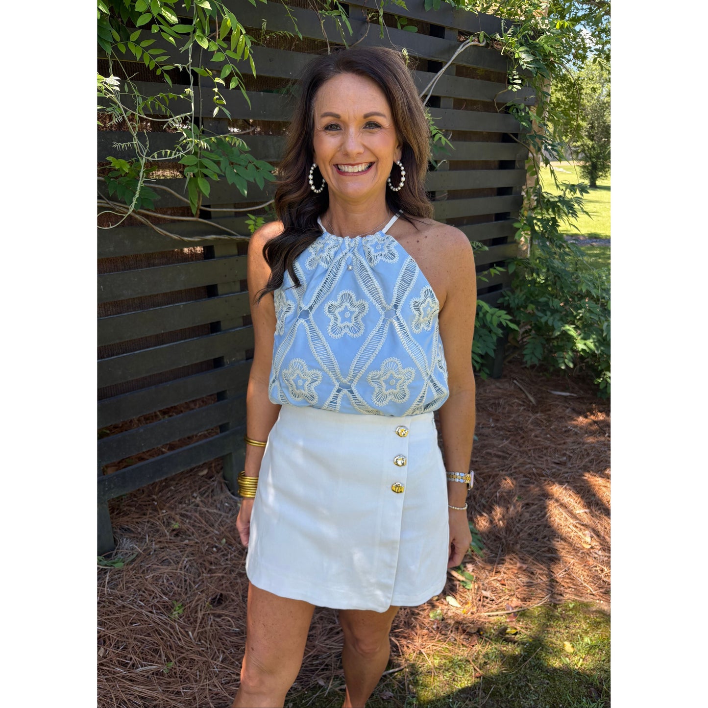 Woman wearing a light blue top and white skirt outdoors