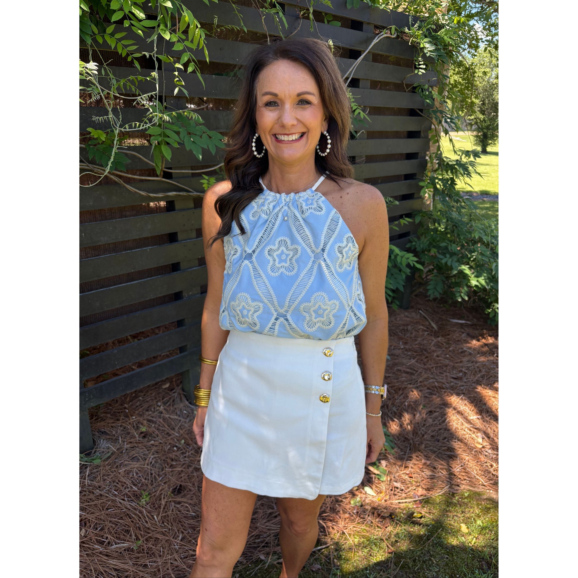 Woman wearing a light blue top and white skirt outdoors