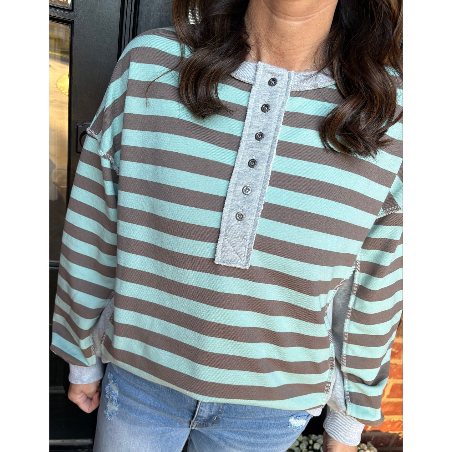 Person wearing a striped shirt with a decorative patch, sitting on a chair.