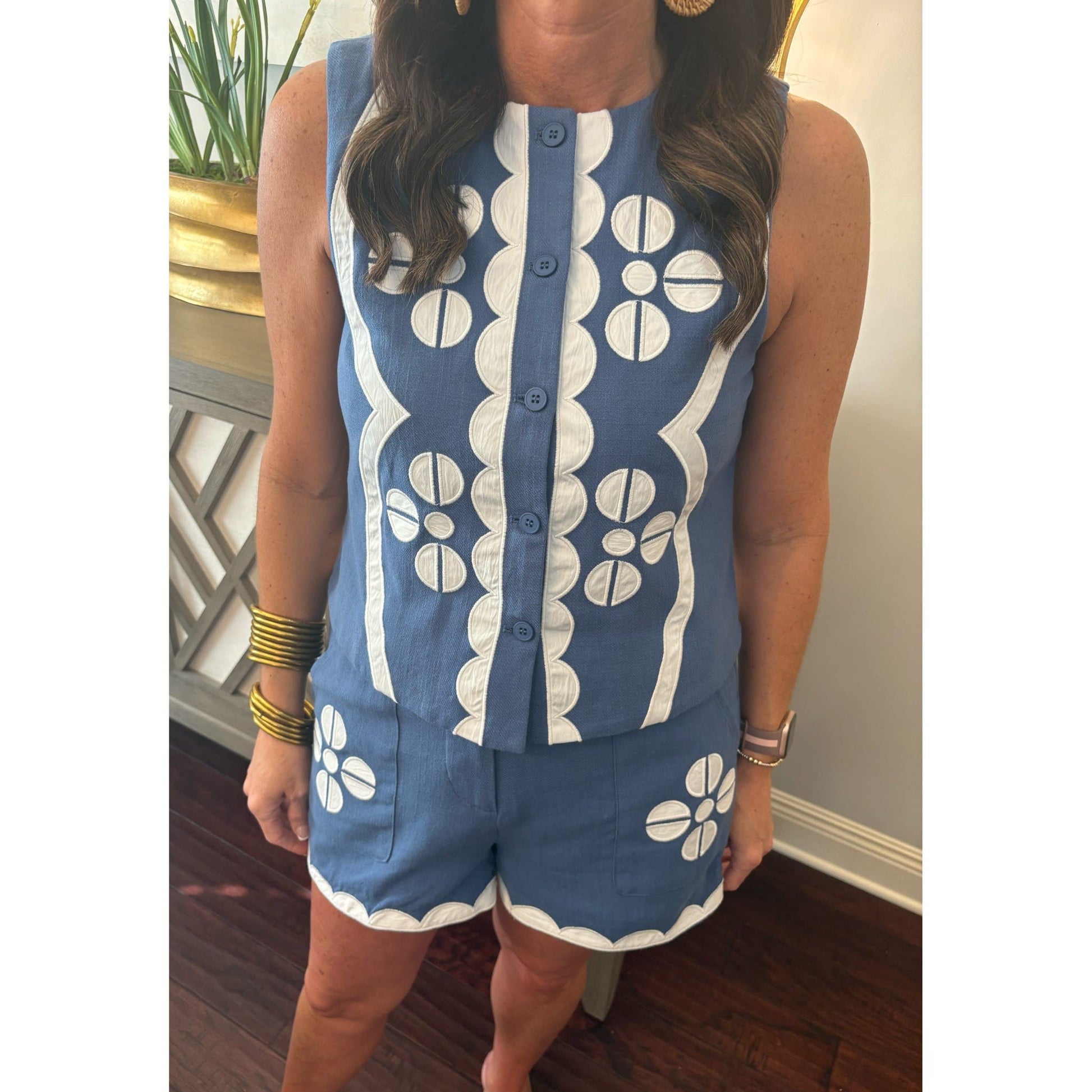 Person wearing a blue and white patterned sleeveless top and shorts set indoors.