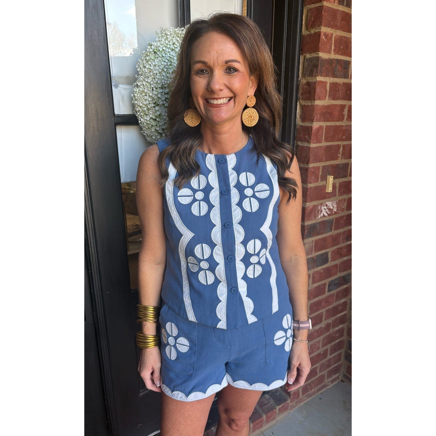 Woman wearing a blue and white patterned romper standing in front of a brick wall.