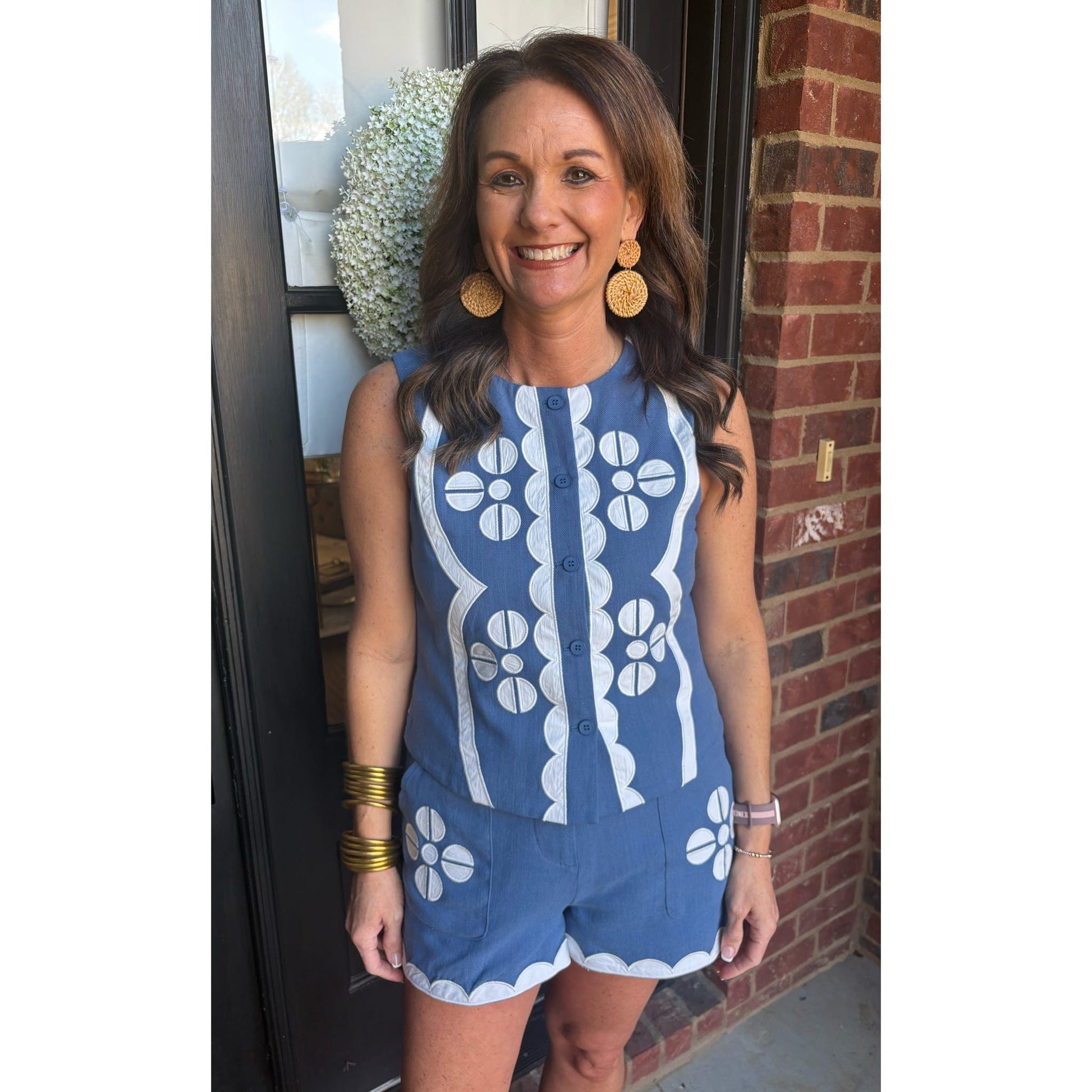 Woman wearing a blue and white patterned romper standing in front of a brick wall.