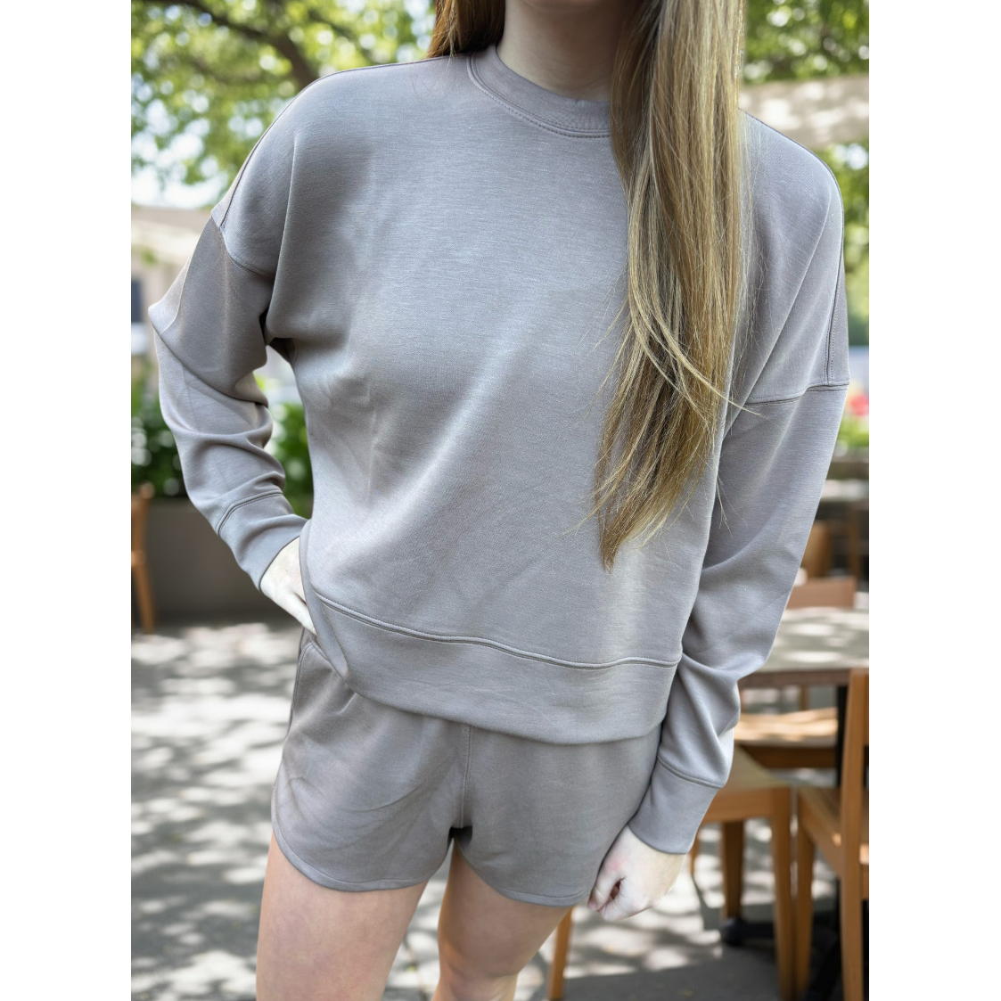 Person wearing a gray sweatshirt and shorts set outdoors.