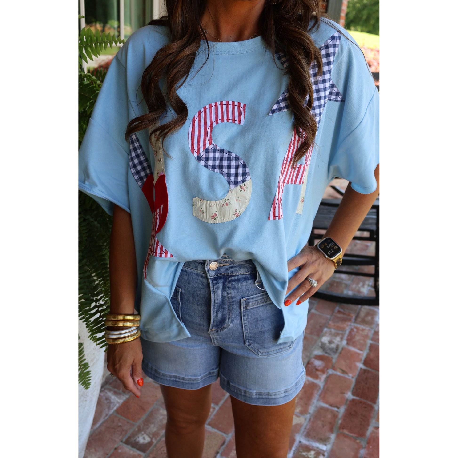 Light blue t-shirt with red, white, and blue pattern worn by a person outdoors.