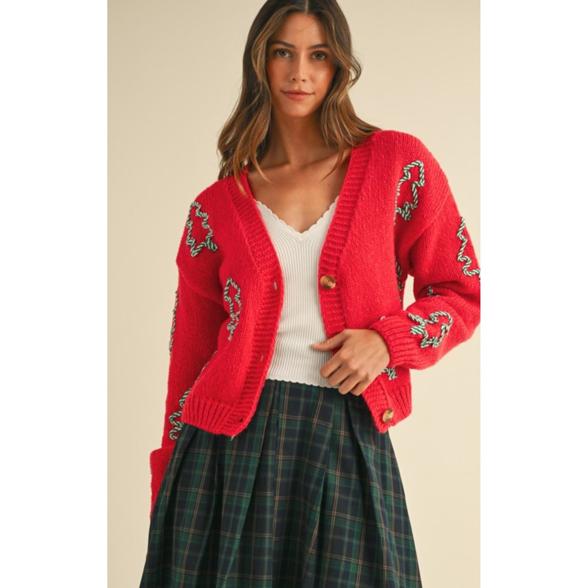 Woman wearing a red cardigan with green patterns on a beige background