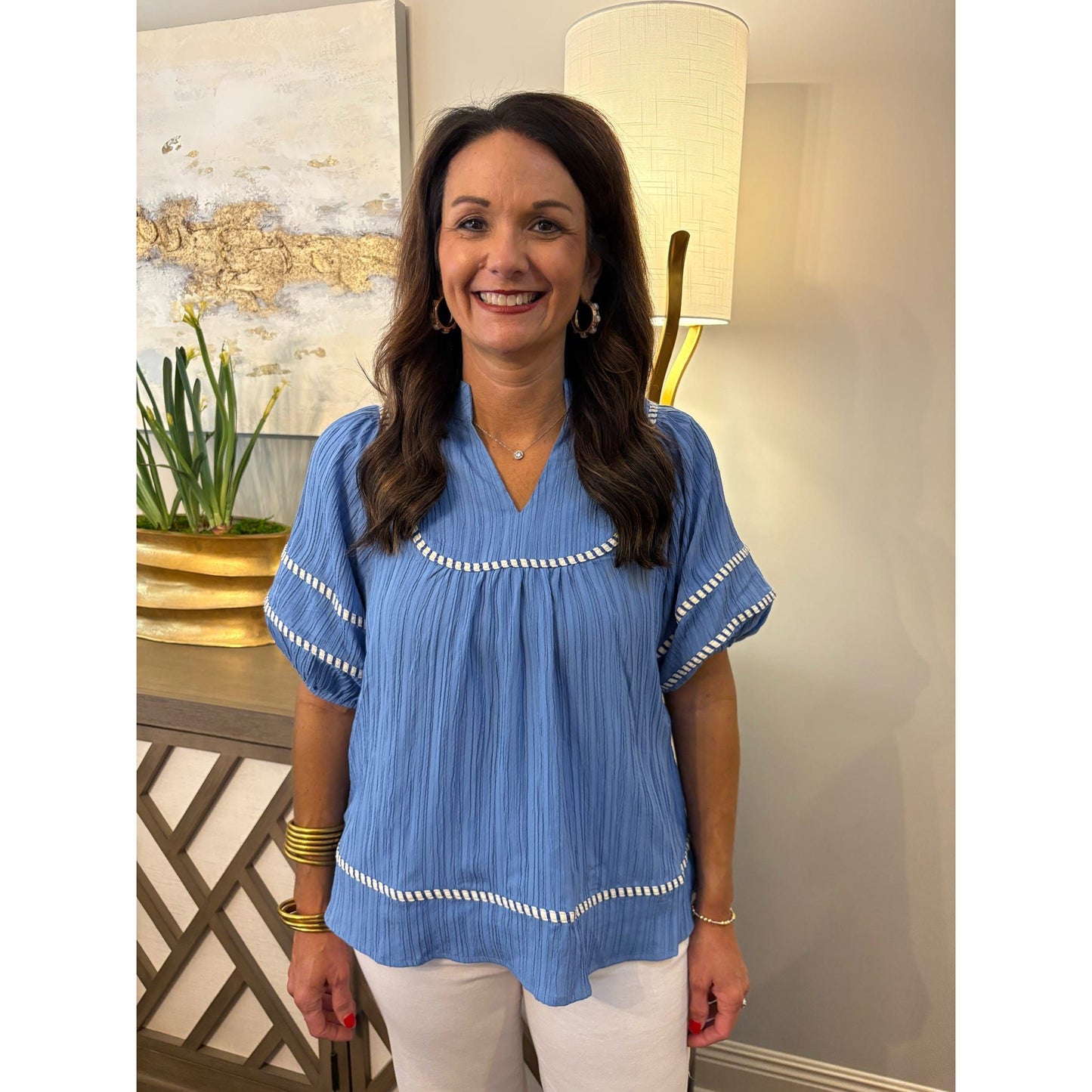 Woman wearing a blue blouse with white trim indoors