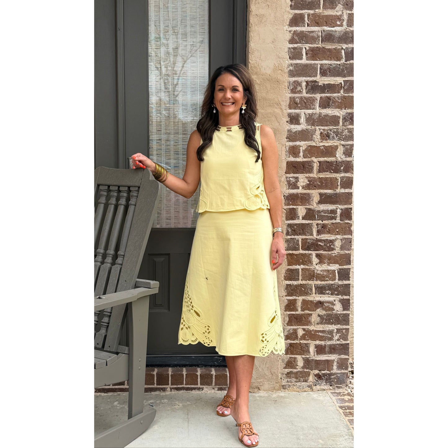 Woman in a yellow dress standing outdoors next to a brick wall.