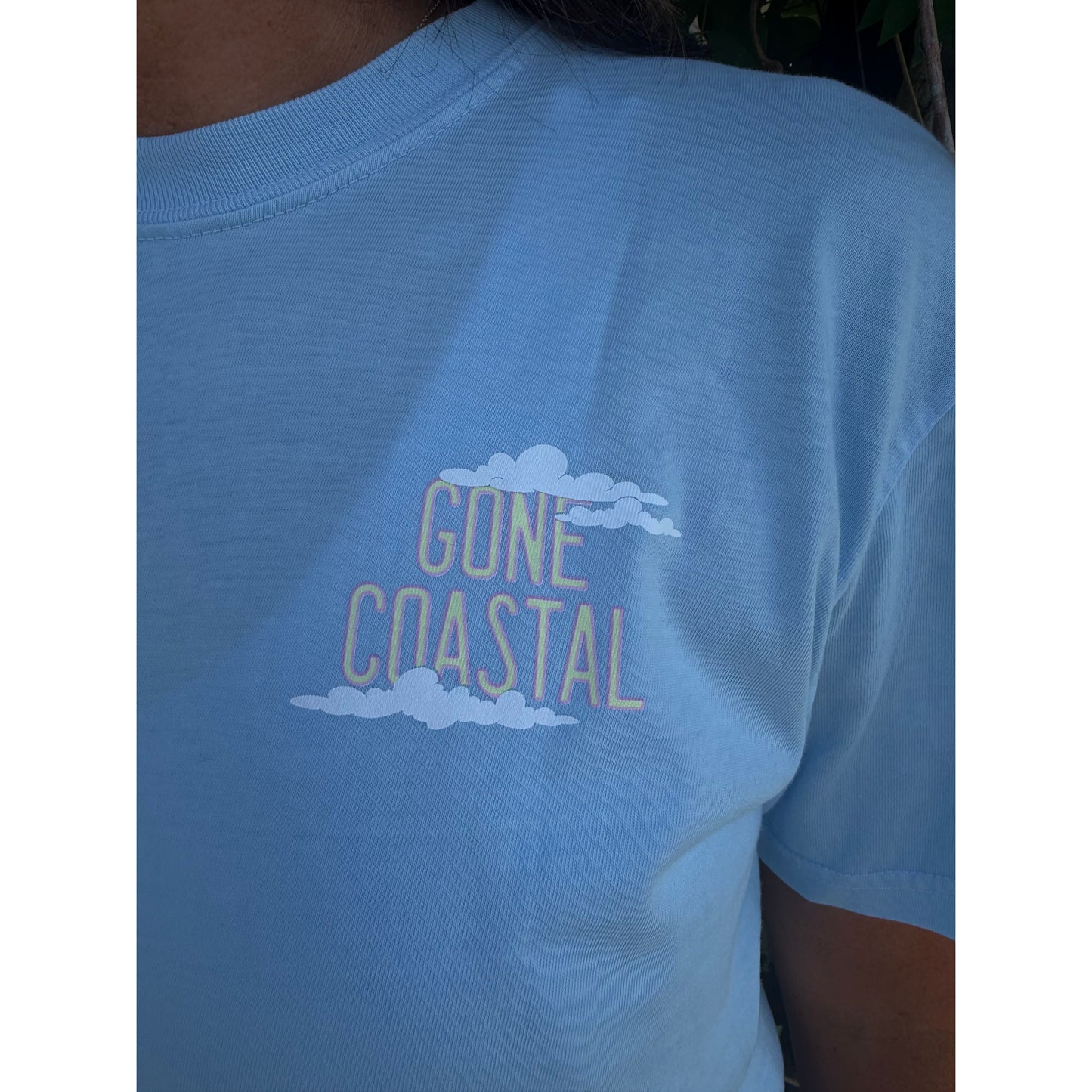 Light blue shirt with 'Gone Coastal' text and cloud design on a person wearing it.