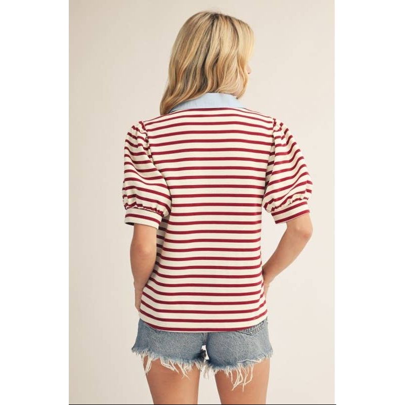 Person wearing a red and white striped shirt with denim shorts on a plain background
