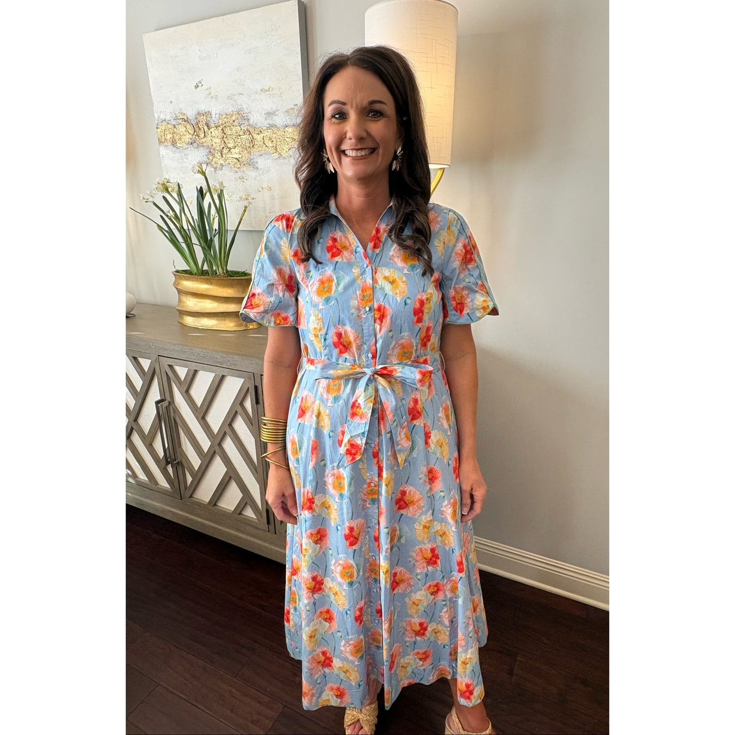 Woman wearing a floral dress in a room with decor elements.