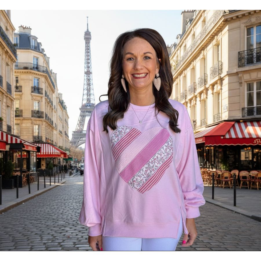 Woman wearing a pink long-sleeve top with a patterned design.