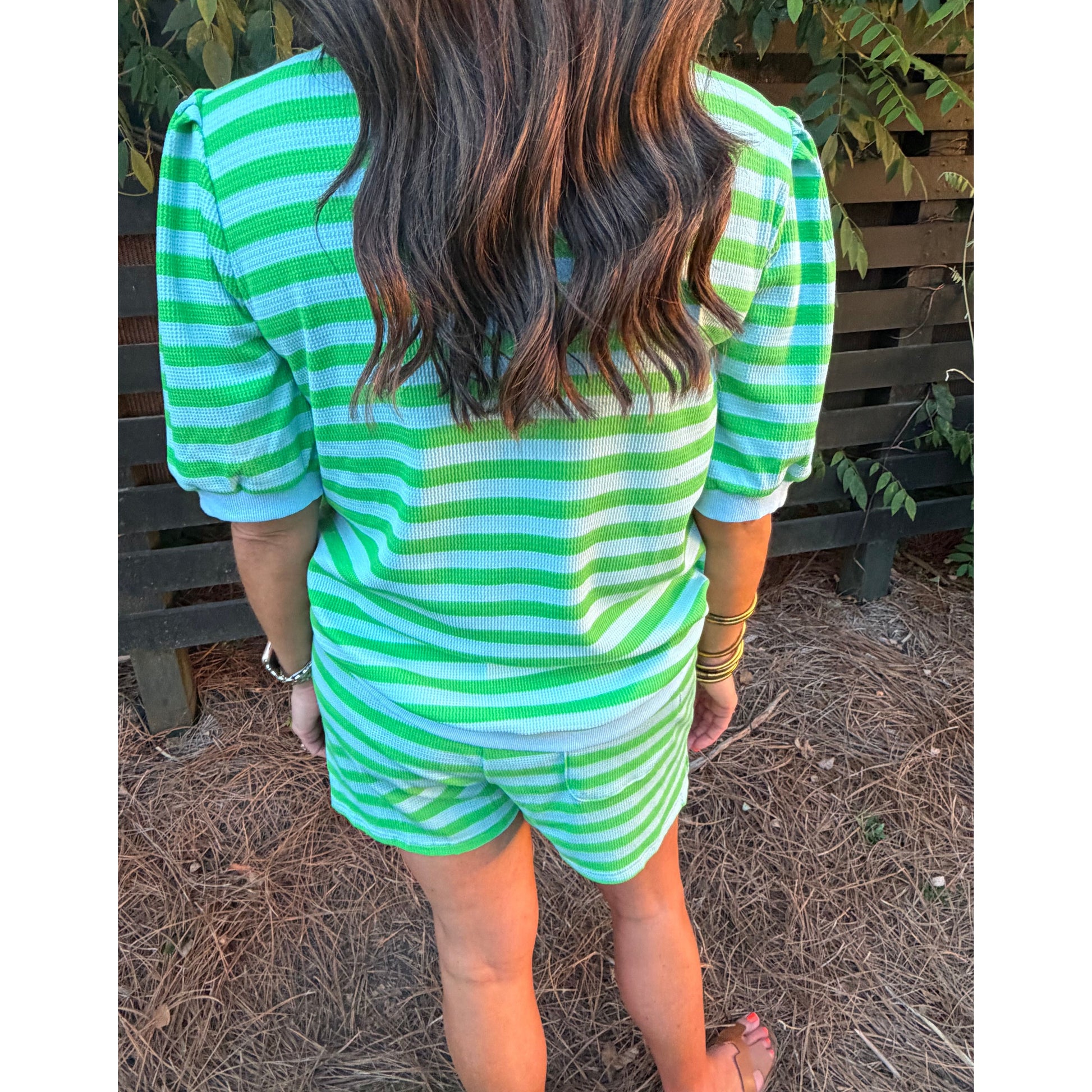 Person wearing a green and white striped outfit standing outdoors.
