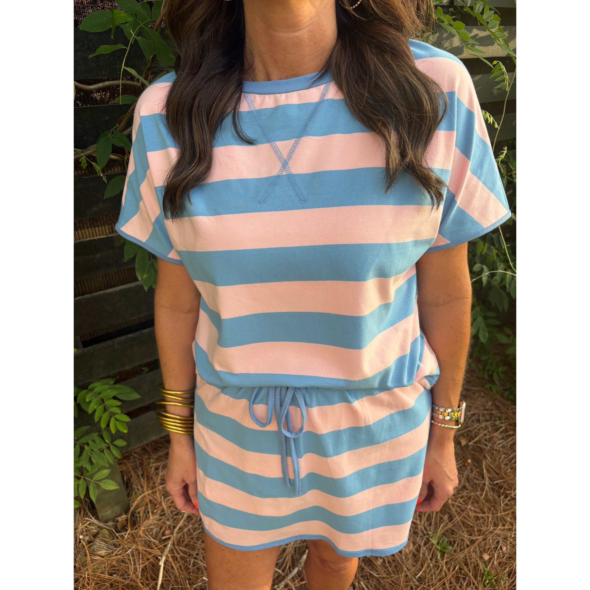 Person wearing a blue and pink striped dress with a blurred background