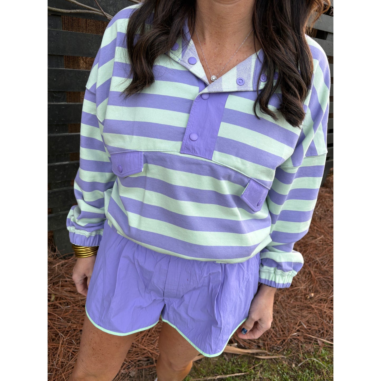 Person wearing a purple and green striped shirt outdoors