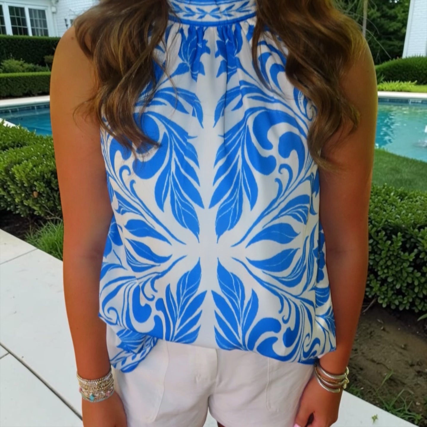 Person wearing a blue and white patterned sleeveless top outdoors.