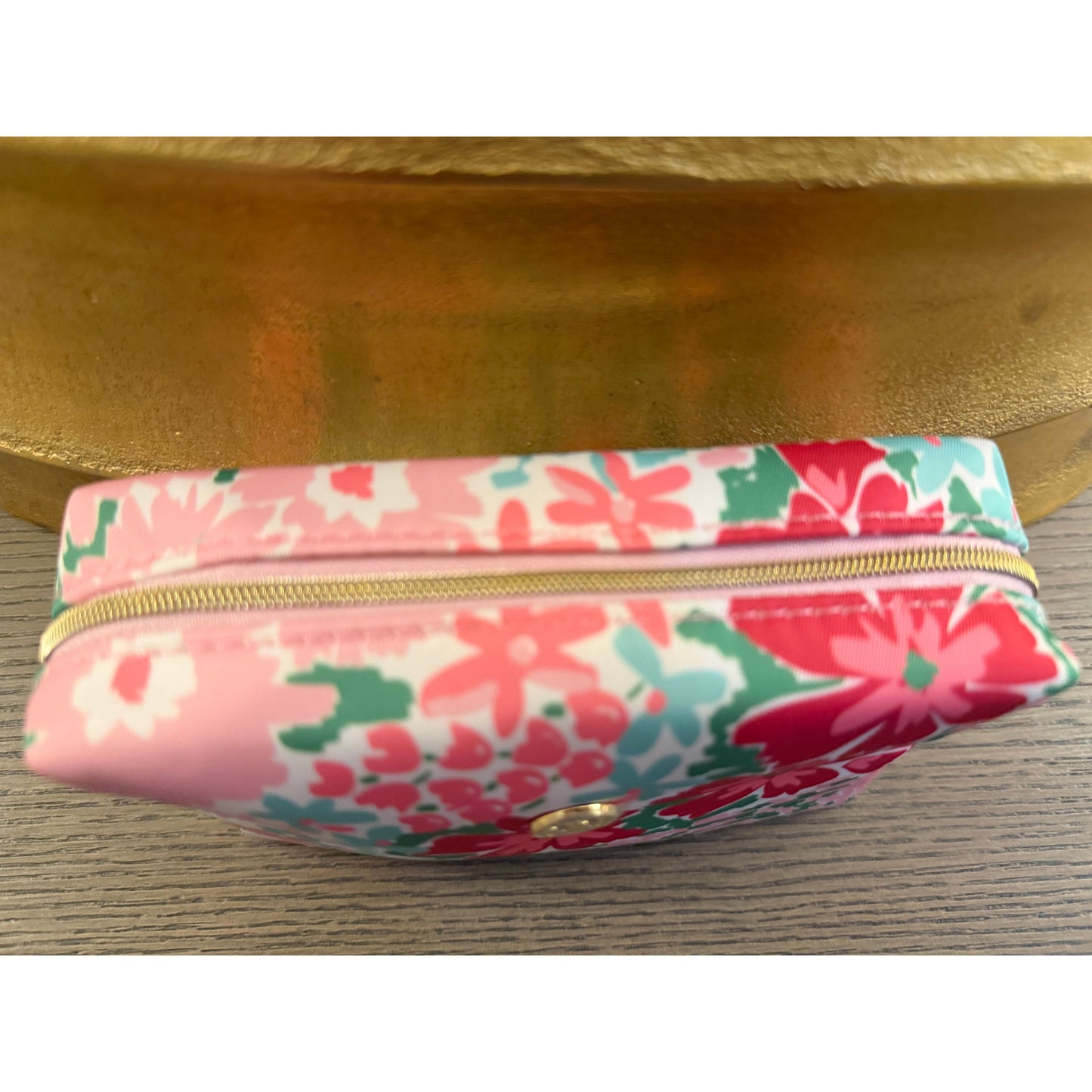 Floral-patterned pouch with a gold zipper on a wooden surface