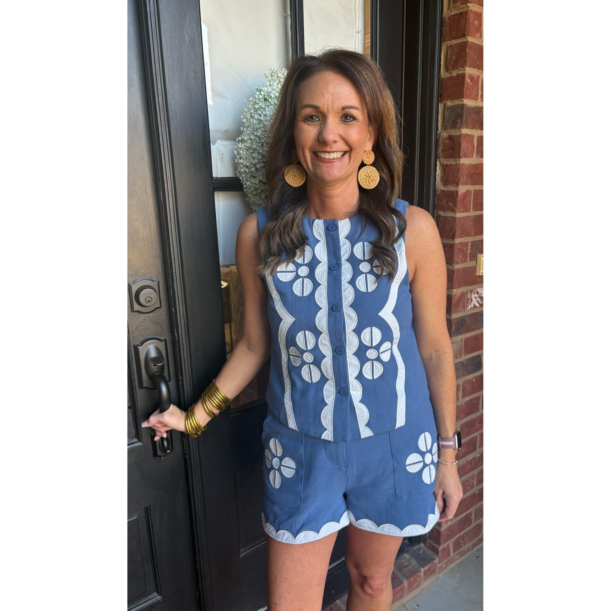 Woman in a blue and white patterned romper standing outside a building.