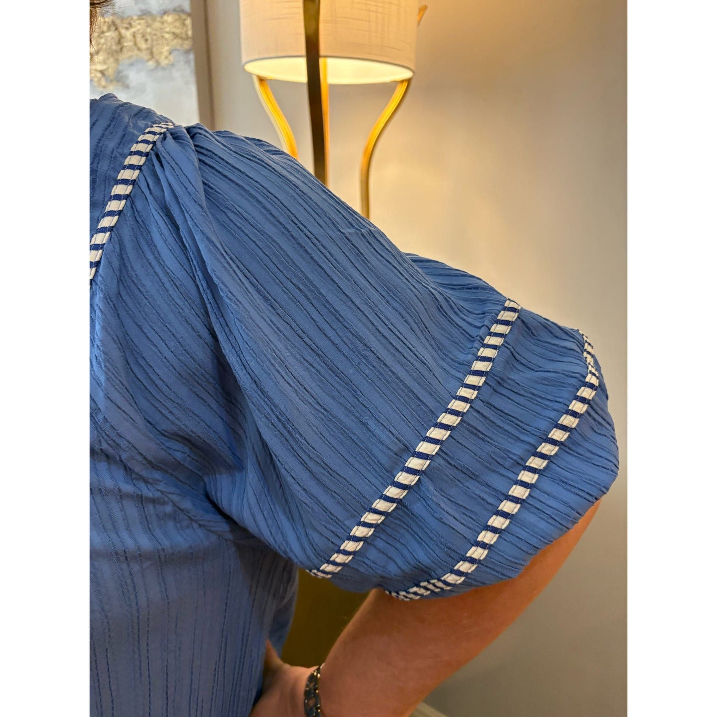 Blue pleated garment with white trim on a blurred background