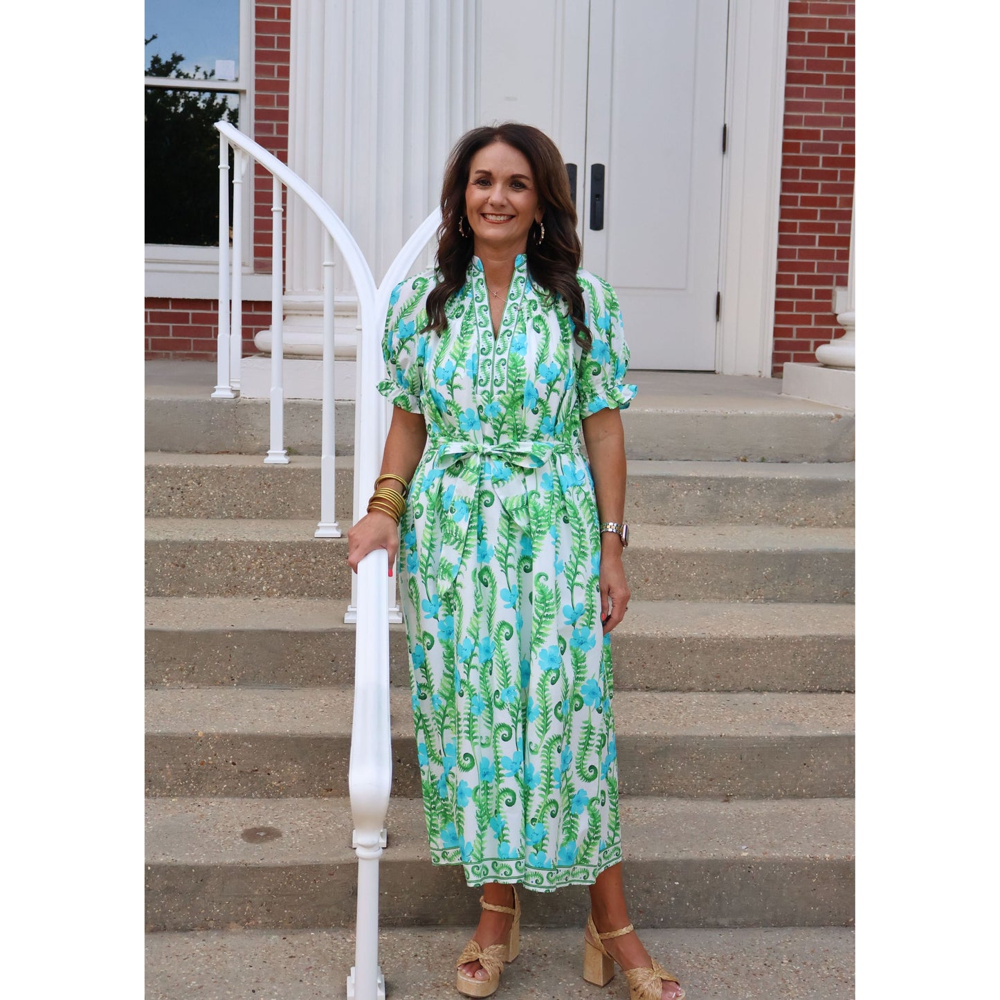 Woman in a green dress standing on steps with a building in the background