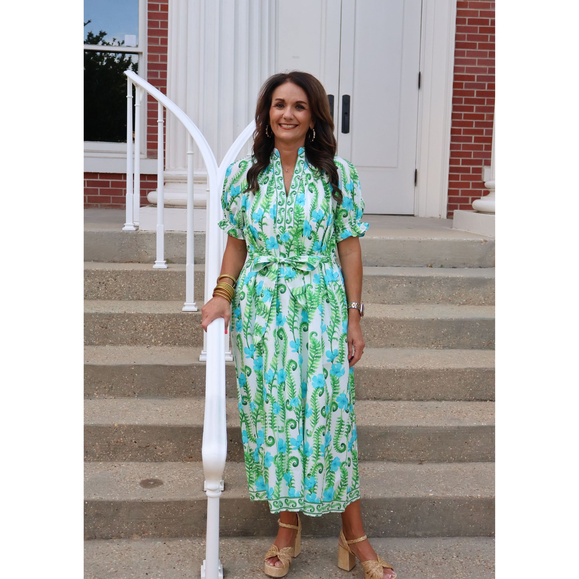 Woman in a green dress standing on steps with a building in the background