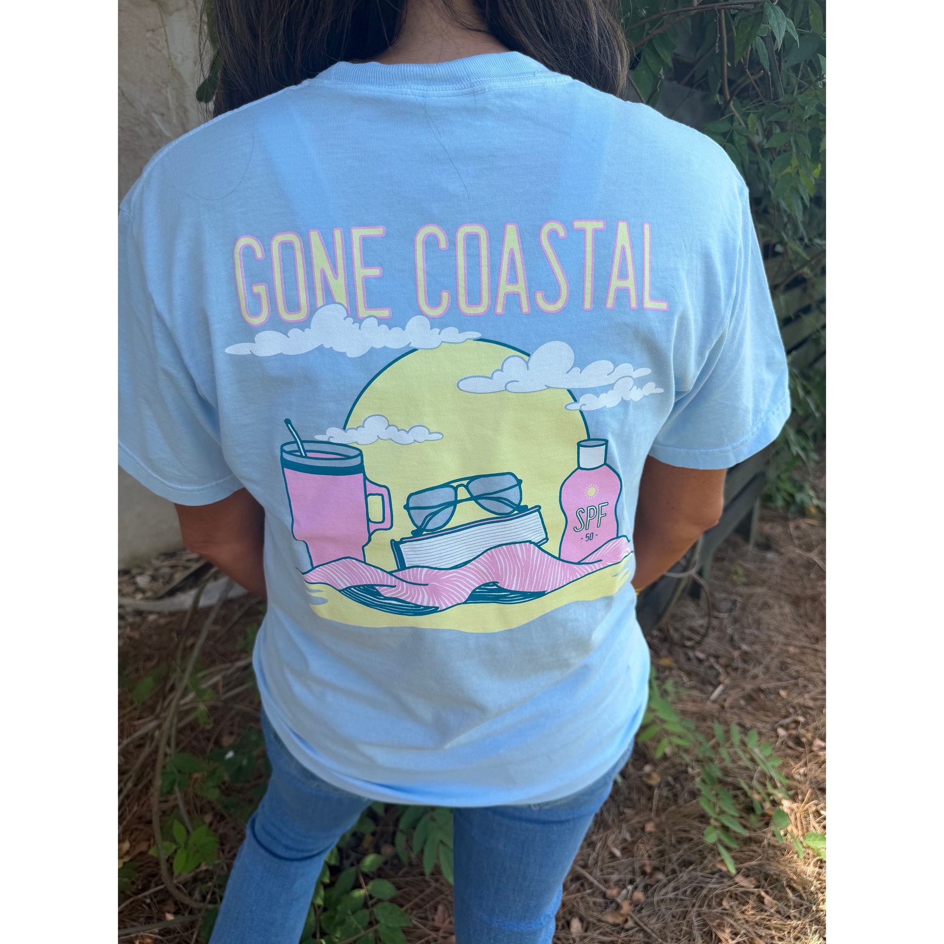 Person wearing a light blue t-shirt with 'Gone Coastal' design featuring a beach scene.