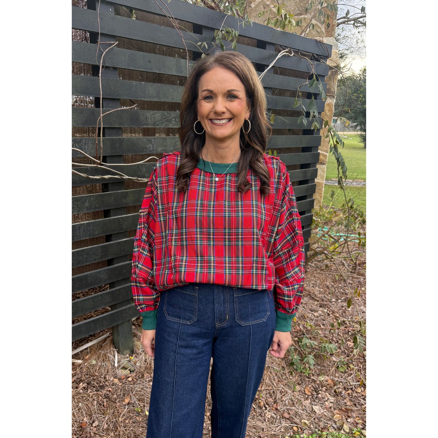 Person wearing a red plaid jacket sitting on a metal bench outdoors.