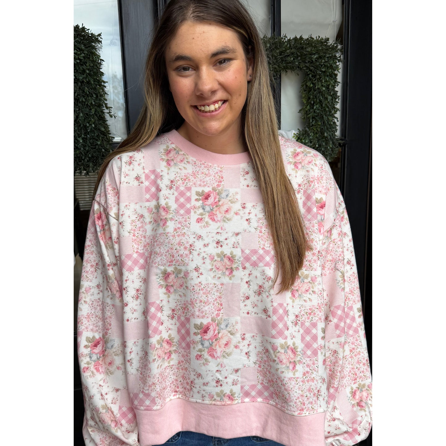 Person wearing a pink floral sweatshirt standing outdoors.