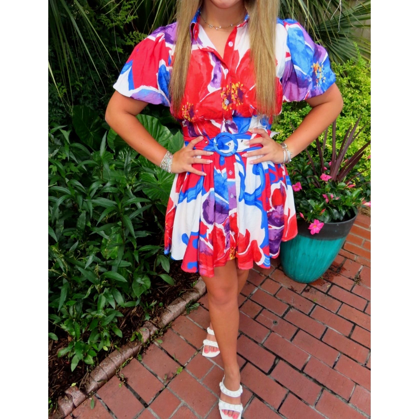 Person wearing a colorful floral dress standing outdoors with plants in the background