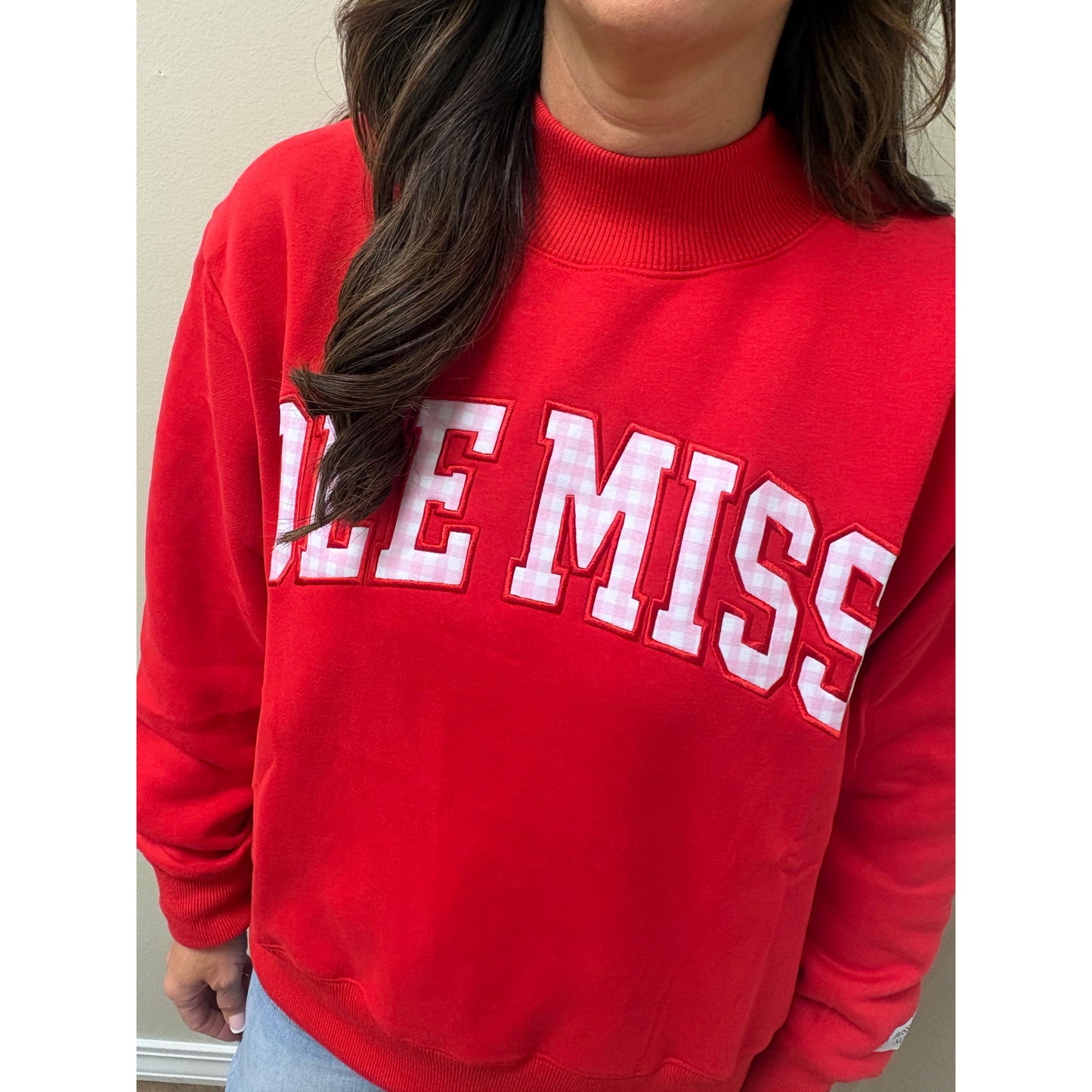 A close-up of a person wearing a bright red sweatshirt with 'ODE MISS' in large white varsity-style letters outlined in red across the chest.