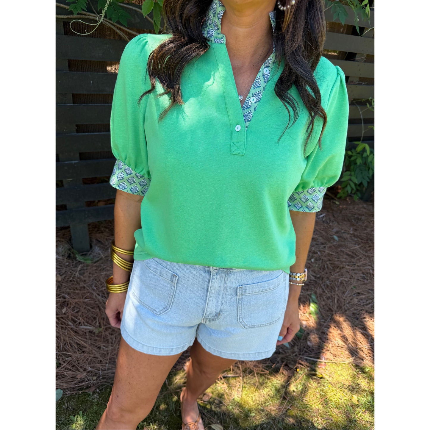 Person wearing a green shirt and light blue shorts outdoors