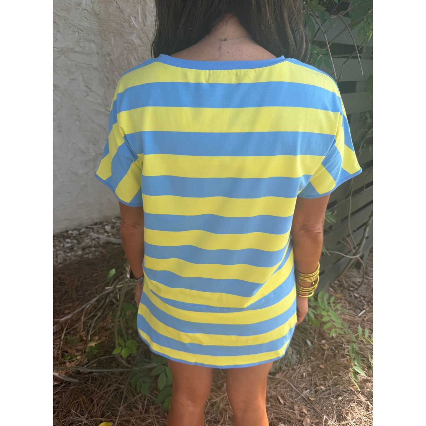 Person wearing a blue and yellow striped dress standing outdoors.