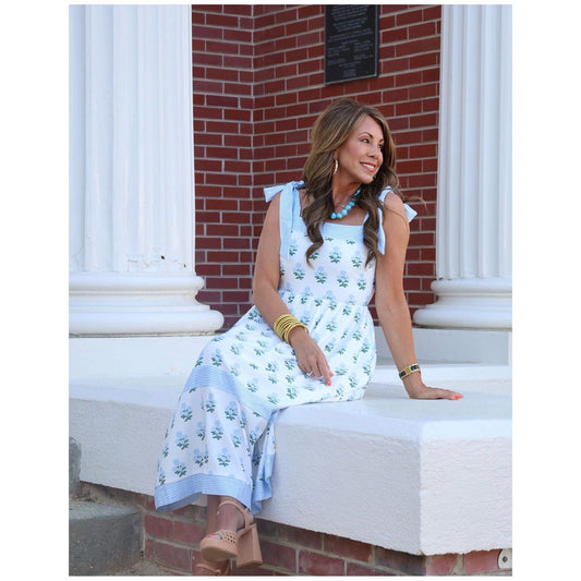 Woman in a floral dress sitting on steps with a brick wall background