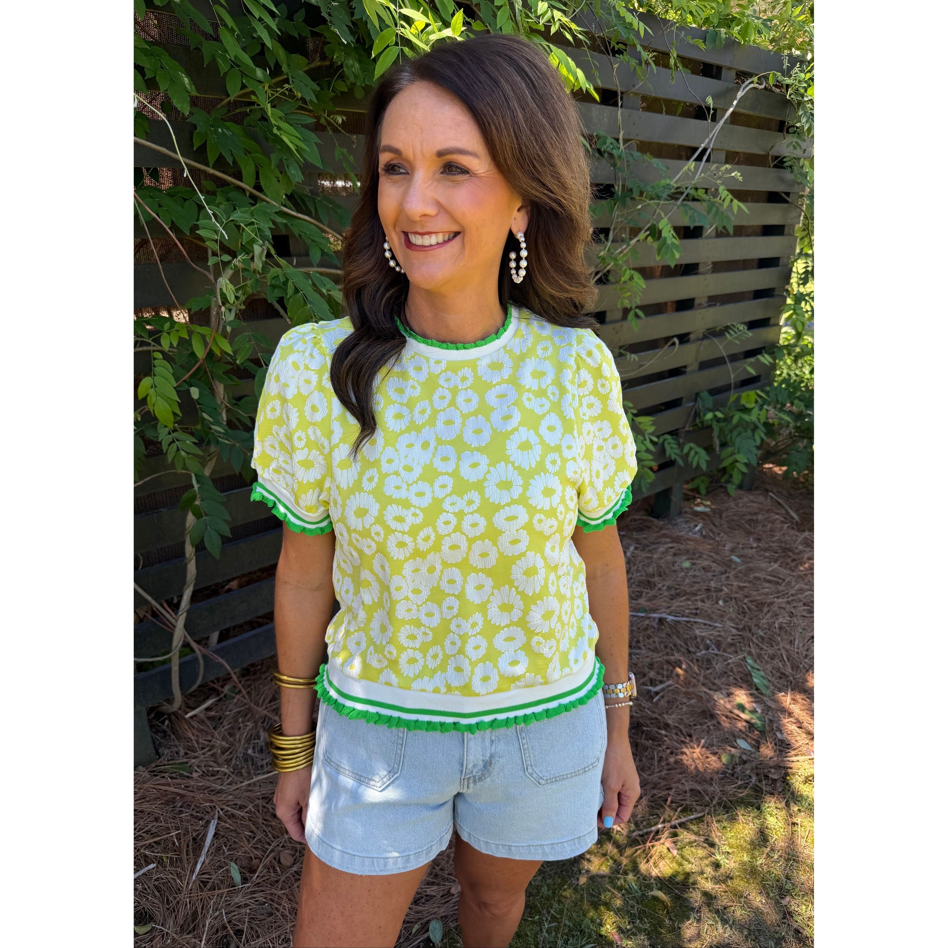Woman wearing a yellow floral top and white shorts outdoors